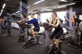Young people doing exercises on elliptical trainer in gym Royalty Free Stock Photo