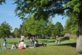 Young people & famlies sitting on grass during sunny weather Royalty Free Stock Photo