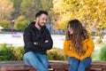 Young people on a first date sitting on a wooden bench in a park and laughing