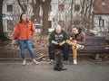 Young people, generation Y men and women, sitting on a bench checking their smartphones and looking at its content