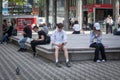 Young people, generation Z, slovenes, boys and girls sitting on a bench watching their smartphones and looking at its content