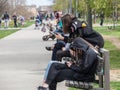 Young people, generation Z teenager girls, sitting on a bench watching their smartphones and looking at its content in the street