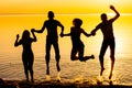 Young people, guys and girls, are jumping against the sunset background, silhouettes Royalty Free Stock Photo