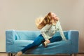 Fashionable girl wearing denim relaxing on couch. Royalty Free Stock Photo