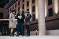 Young people having a business discussion outside an office building at night, illuminated by warm festive lights. Royalty Free Stock Photo