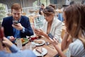 Young people having unsocial lunch in restaurant, using their cell phones and not talking to each other. social issues, victims of Royalty Free Stock Photo