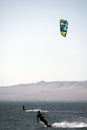 people kitsurfing in a paracas bay of peru with blue water and drops in the air and mountains in the background-june 2020
