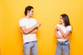 Young people man and woman in basic clothing laughing and pointing fingers at each other isolated over yellow background Royalty Free Stock Photo