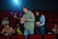 Young people, man and woman dislike the movie, leaving cinema auditorium during the session. Audience looking irritated