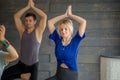 Young people with personal trainer doing yoga exercises on mat in gym studio Royalty Free Stock Photo