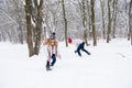 Young people play snowballs in winter forest