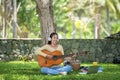 Young people playing guitar and drinking coffee after working and education on laptop in morning relax at nature garden home. Royalty Free Stock Photo