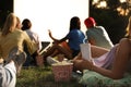 Young people with popcorn and drink watching movie in open air cinema