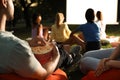 Young people with popcorn watching movie in open air cinema. Space for text