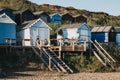 Young people relax by the colourful beach huts in Milford on Sea, New Forest, UK