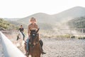 Young people riding horses inside corral - Wild couple having fun in equestrian ranch  - Training, culture, passion, excursion, Royalty Free Stock Photo