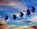 Young people are seen riding a swing chair ride with a beautiful sky Royalty Free Stock Photo