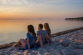 Young people sit on the beach and watch the sunset Royalty Free Stock Photo