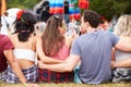 Young people sitting outdoors at a music festival, back view Royalty Free Stock Photo