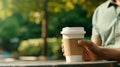 Young people sitting in the park and enjoy coffee in disposable cups