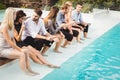 Young people sitting by swimming pool Royalty Free Stock Photo