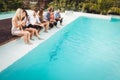 Young people sitting by swimming pool Royalty Free Stock Photo