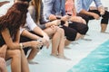 Young people sitting by swimming pool Royalty Free Stock Photo