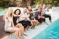 Young people sitting by swimming pool Royalty Free Stock Photo