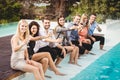 Young people sitting by swimming pool Royalty Free Stock Photo