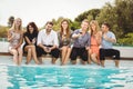 Young people sitting by swimming pool Royalty Free Stock Photo