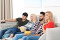 Young people with snacks watching TV on sofa