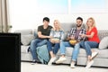 Young people with snacks watching TV on sofa