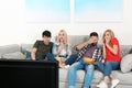 Young people with snacks watching TV on sofa