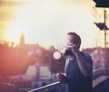 Young people spend time on the terrace of the house, blowing bubbles with the help of vaporizer against backdrop of the sunset
