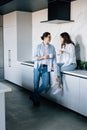 Attractive young woman and handsome man are enjoying spending time together while standing on light modern kitchen with cup of Royalty Free Stock Photo