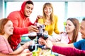 Young people toasting red wine at dinner party on multicolored clothes - Happy drunk friends having fun together Royalty Free Stock Photo