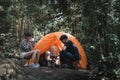 Young People Trekking Group Sitting Relaxed in the Rainforest and Boil Water with a Camp Stove. Campsite Drinking Coffee and Water