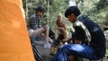 Young People Trekking Group Sitting Relaxed in the Rainforest and Boil Water with a Camp Stove. Campsite Drinking Coffee and Water