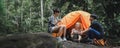 Young People Trekking Group Sitting Relaxed in the Rainforest and Boil Water with a Camp Stove. Campsite Drinking Coffee and Water