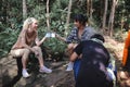 Young People Trekking Group Sitting Relaxed in the Rainforest and Boil Water with a Camp Stove. Campsite Drinking Coffee and Water