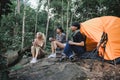 Young People Trekking Group Sitting Relaxed in the Rainforest and Boil Water with a Camp Stove. Campsite Drinking Coffee and Water