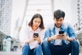 Young people are using smartphone and smiling while sitting on free time. Royalty Free Stock Photo