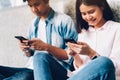 Young people are using smartphone and smiling while sitting on free time. technology concept. Royalty Free Stock Photo