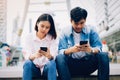 Young people are using smartphone and smiling while sitting on free time. Royalty Free Stock Photo