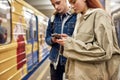 Young people using smartphones while standing at the subway metro station. Couple of teenagers looking focused, using Royalty Free Stock Photo