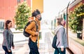 Young people waiting in line practising social distancing at bus city station - New normal transport concept Royalty Free Stock Photo