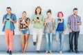 Young people watching on their smart mobile phones leaning on a wall - Generation addicted to new technology Royalty Free Stock Photo