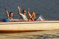 Young people waving from motorboat Royalty Free Stock Photo