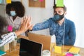 Young people working inside a coworking behind safety plexiglass during coronavirus outbreak - Social distance concept - Focus on