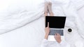 Young people working on laptop and drinking coffee in morning relax mood in winter season. Close up legs women on white bed Royalty Free Stock Photo